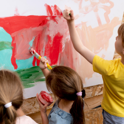 crianças-pintando-com-pínceis-e-tintas-coloridas-em-mural-branco